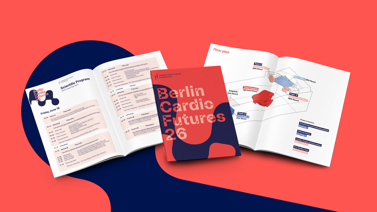 Brosch&uuml;ren und ein Booklet f&uuml;r &bdquo;Berlin Cardio Futures 26&ldquo; vor rotem Hintergrund mit dunkelblauem Kreis. Die aufgeschlagenen Seiten zeigen ein Konferenzprogramm sowie einen Lageplan mit Illustrationen in Rot, Blau und Beige.
